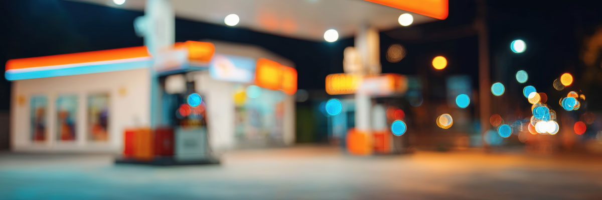 Blurred gas station glowing with colorful lights at night