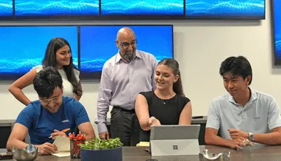 Five colleagues collaborating around a laptop in modern office