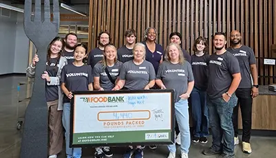 Volunteers holding large check at food bank donation event