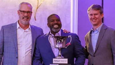 Three men smiling while holding a trophy at an event