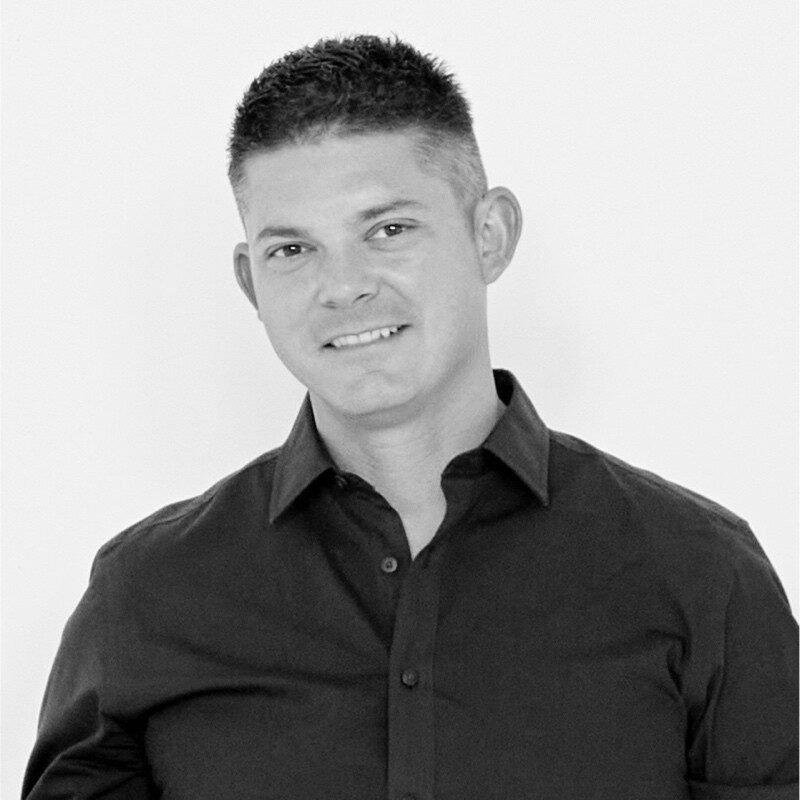Professional black and white headshot of smiling man in dark shirt